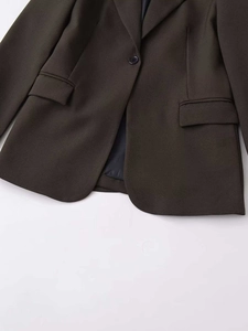 Detailed close-up of dark olive blazer featuring a notched lapel and single-button closure