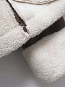 Detail of white faux shearling jacket with dark brown leather trim and fine stitching