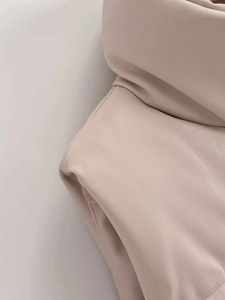 Detailed close-up of beige faux leather texture and clean stitching on a padded vest