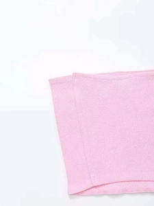 Detailed close-up of light pink ribbed knit fabric showing soft texture and stitching