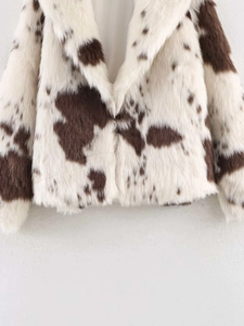 Detail of faux fur cow print jacket featuring oversized lapel and soft brown patches