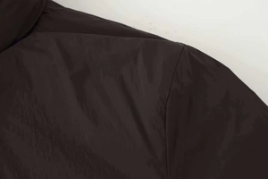 Macro detail of dark synthetic fabric texture and smooth stitching on a loose padded jacket
