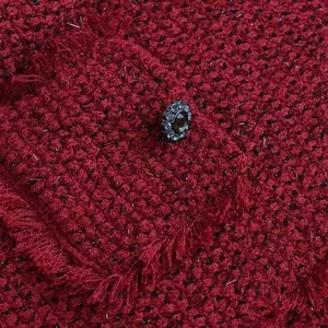 Gros plan détaillé d'une veste en tweed rouge foncé avec texture tissée et bouton orné