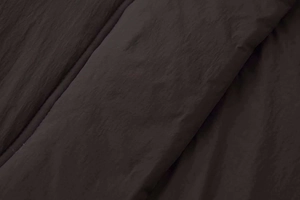 Close-up of charcoal grey quilted puffer jacket fabric with matte horizontal stitching