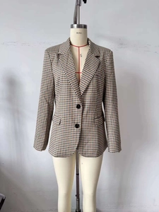 Dettaglio di un blazer scozzese da donna con revers a dente e chiusura classica a bottoni