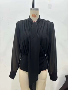 Dettaglio camicetta in chiffon nero con fiocco al collo e trama plissettata