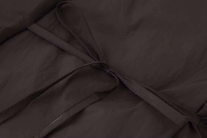 Detail view of adjustable side drawstrings and smooth fabric texture on brown puffer jacket