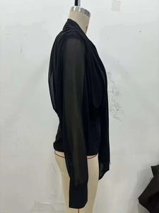 Dettaglio della camicetta nera in chiffon con maniche patchwork trasparenti e fiocco al collo