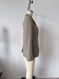 Dettaglio di un blazer classico a quadri marroni con revers e tasca laterale rifinita
