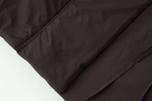 Close-up of dark brown quilted fabric texture with waterproof synthetic finish and stitching