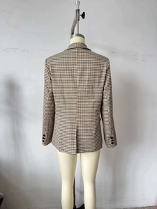 Dettaglio del retro di un blazer a quadri marrone con cucitura centrale e bottoni sulle maniche