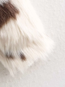 Detailed macro view showing the soft texture and cow print pattern of faux fur coat fabric