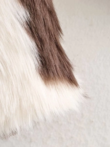 Detailed close-up of brown and white cow print faux fur jacket with soft fluffy texture