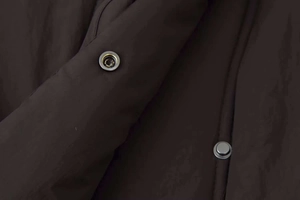 Close-up of silver metal snap buttons on a thick charcoal winter puffer jacket