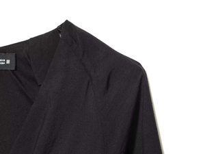 Detailed view of V-neck collar and white woven label on black summer waist dress