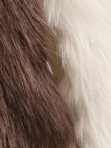 Close-up detail of soft faux fur texture with brown and cream cow print pattern