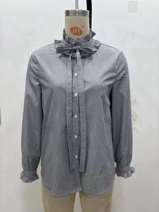 Detailed view of striped shirt featuring a ruffled stand collar and elegant bow tie neck