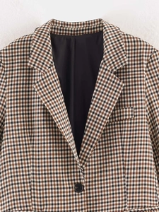 Dettaglio del rever del blazer a quadri marrone con bottone e trama del tessuto intrecciato