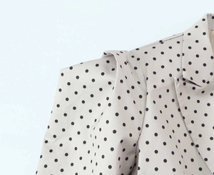 Gros plan sur l'épaule structurée et le revers d'un blazer beige à pois noirs