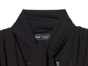 Dettaglio del colletto della camicetta in chiffon nero con fiocco ed etichetta