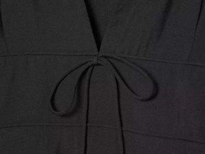 Detailed macro view of the black V-neckline featuring a delicate bow tie and fine stitching