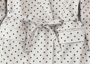Détail d'un blazer à pois avec une ceinture à nouer et une poche à rabat fonctionnelle