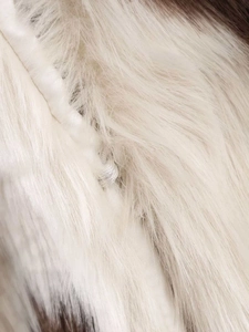 Macro shot of faux fur material with brown cow print pattern and white satin piping detail
