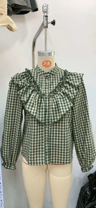 Detailed view of green gingham shirt featuring layered ruffles and a small stand collar