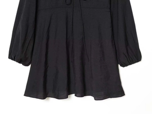 Detailed view of black high-waisted dress with tie-neck and pleated lantern sleeves