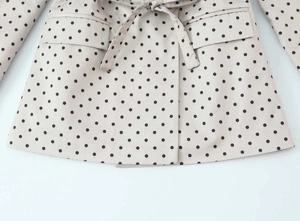 Détail d'un blazer beige à pois avec ceinture nouée à la taille et poches à rabat