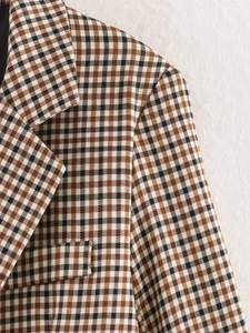 Dettaglio del rever a lancia e della trama del tessuto scozzese marrone del blazer casual