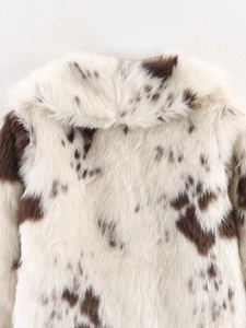 Close-up of fluffy faux fur jacket featuring brown cow print and wide notched lapels