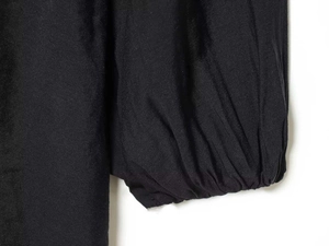 Detailed close-up of elastic ruffled cuffs on a black summer dress with smooth fabric