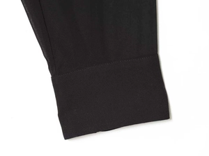 Dettaglio del polsino della camicetta di chiffon nera con cuciture fini e trama del tessuto