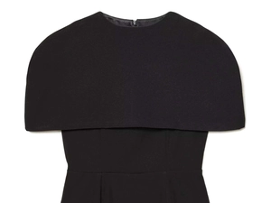 Detail of elegant black cape-style dress showing layered shoulder pads and hidden zipper