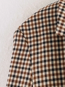 Dettaglio ravvicinato del tessuto pied de poule marrone con cuciture su un blazer a quadri