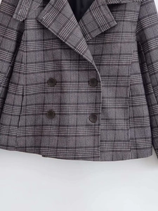 Detail of grey plaid double-breasted blazer with textured woven fabric and peak lapels
