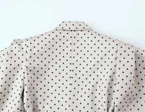 Vue détaillée d'un blazer beige à pois noirs montrant le revers et les coutures