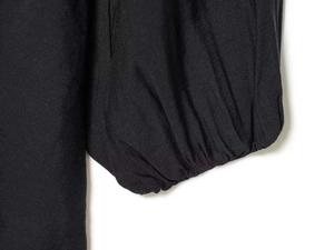 Detail of elegant black dress showing ruched elastic cuffs and soft fabric texture