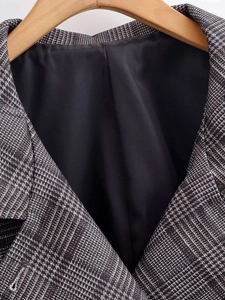 Detailed close-up of plaid blazer collar with premium black lining on a wooden hanger