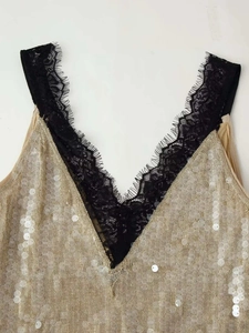 Close-up of golden sequin dress featuring deep V-neckline and black eyelash lace trim
