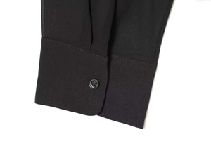 Dettaglio del polsino in chiffon nero con bottone lucido e cuciture di alta qualità