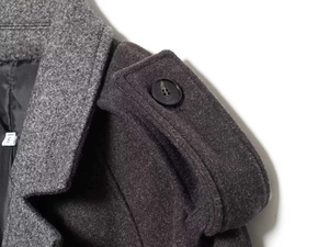 Detailed close-up of dark grey wool coat featuring epaulettes and classic black buttons