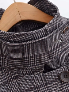 Close-up of retro plaid blazer detail featuring a high collar buckle and resin buttons
