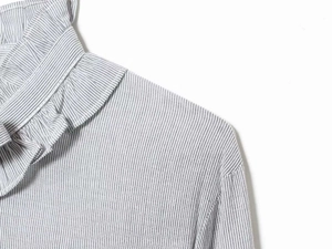 Detailed macro shot of fine striped fabric and ruffled collar design on a women blouse