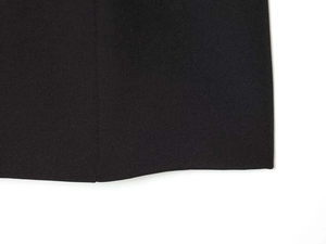 Detailed close-up of vertical stitching and hem finish on black woven dress fabric
