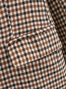 Dettaglio macro del motivo pied-de-poule e della tasca sul blazer autunnale chic