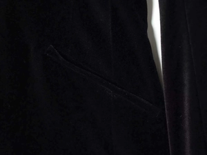 Detail view of smooth black velvet fabric with satin luster on a classic flat pocket design