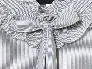 Detail of ruffled collar and drawstring tie on a navy blue pinstripe blouse