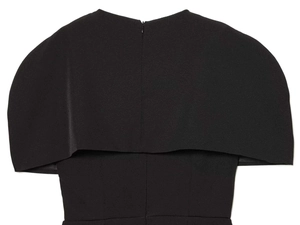 Detail view of black dress featuring a layered capelet design and invisible back zipper